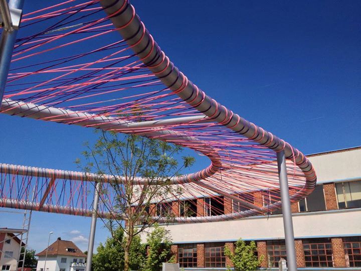 Stahlbau Kunstwerk Kelsterbach mit gebogenen Großrohren bespannt mit bunten Seilen